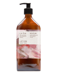 A 500ml recycled amber glass pump bottle of Roseum Hand & Body Lotion with a label featuring 'Flamingos' artwork by Meinke Flessemen and the text 'roséum' part of the rose geranium botanical, Pelargonium roseum.