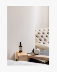 Bottles of La-Eva jasmina essential oil and jasmina universal oil on a wooden block next to books with a blurred background