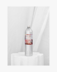 Lifestyle:A tall, slender aluminium bottle of Roseum hand and body wash sustainable refill. Label featuring Meinke Flessemen artwork.