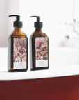 Lifestyle: Two recycled amber glass pump bottles of Roseum Hand & Body Wash and Lotion with bespoke artwork for ARC architecture by artist Beatrice Hassel McCosh.