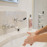 lady washing her hands with La-Eva Roseum face and body wash presented in aa 200ml aluminium bottle