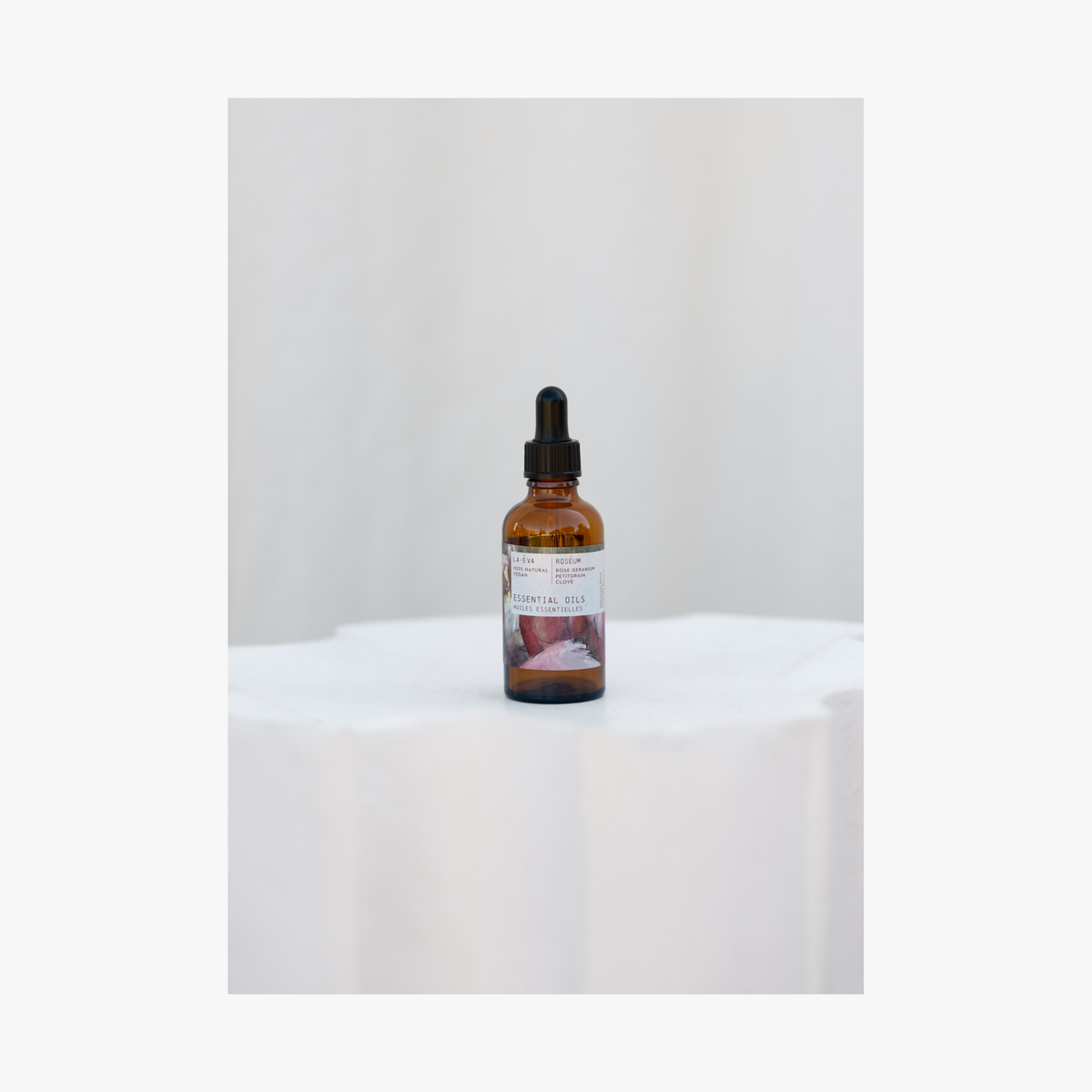 A bottle of Roseum Essential Oils with a dropper, on a white background.