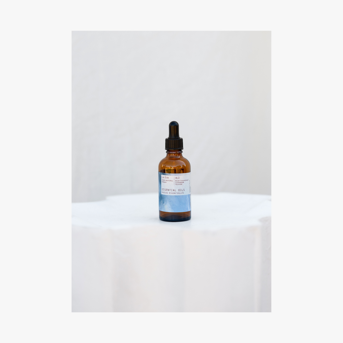 La-Eva blu essential oil in amber glass bottle with pippette. Label features artwork by Rose-Marie Caldicott