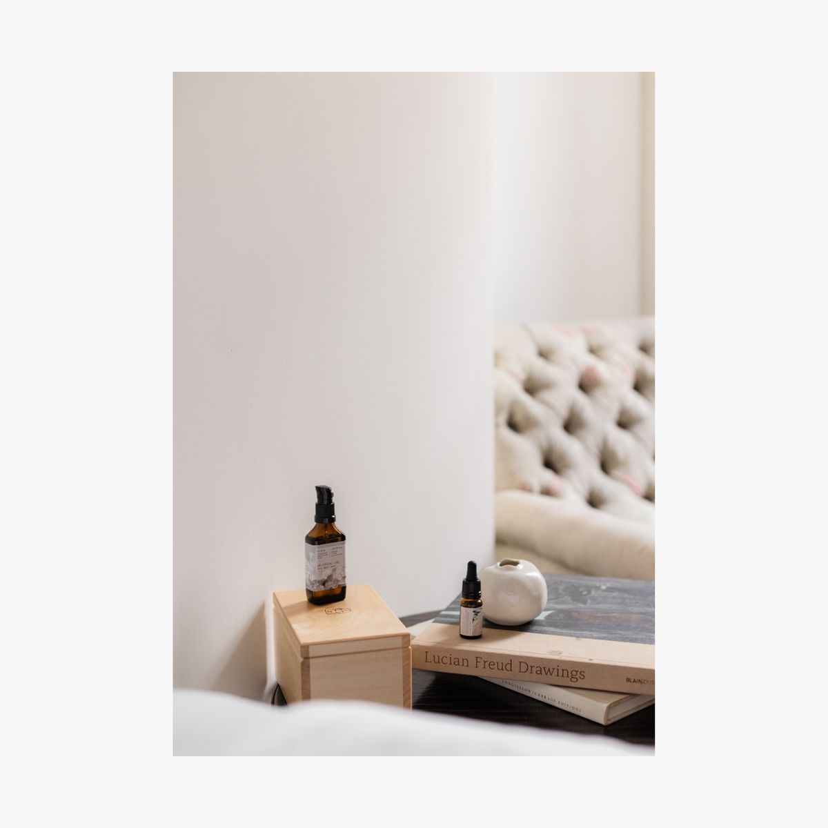 Bottles of La-Eva jasmina essential oil and jasmina universal oil on a wooden block next to books with a blurred background