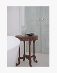 Lifestyle: A standing pouch of La-Eva Linden salts with Valeska Hykel artwork label sits on a round wooden table beside a small black dish in a softly lit interior setting
