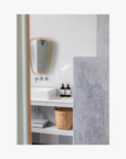Bathroom shelf with bottles of the La-Eva refillable amenities spice collection and a vase against a light grey wall. Featuring artwork by Emma Cassi