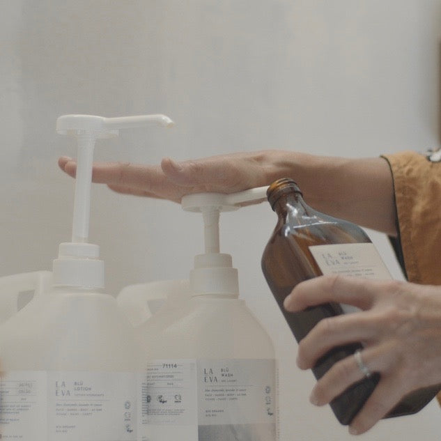 A 5-litre bottle of La-Eva Blu hand and body wash and lotion being filled into recycle amber glass pump bottle