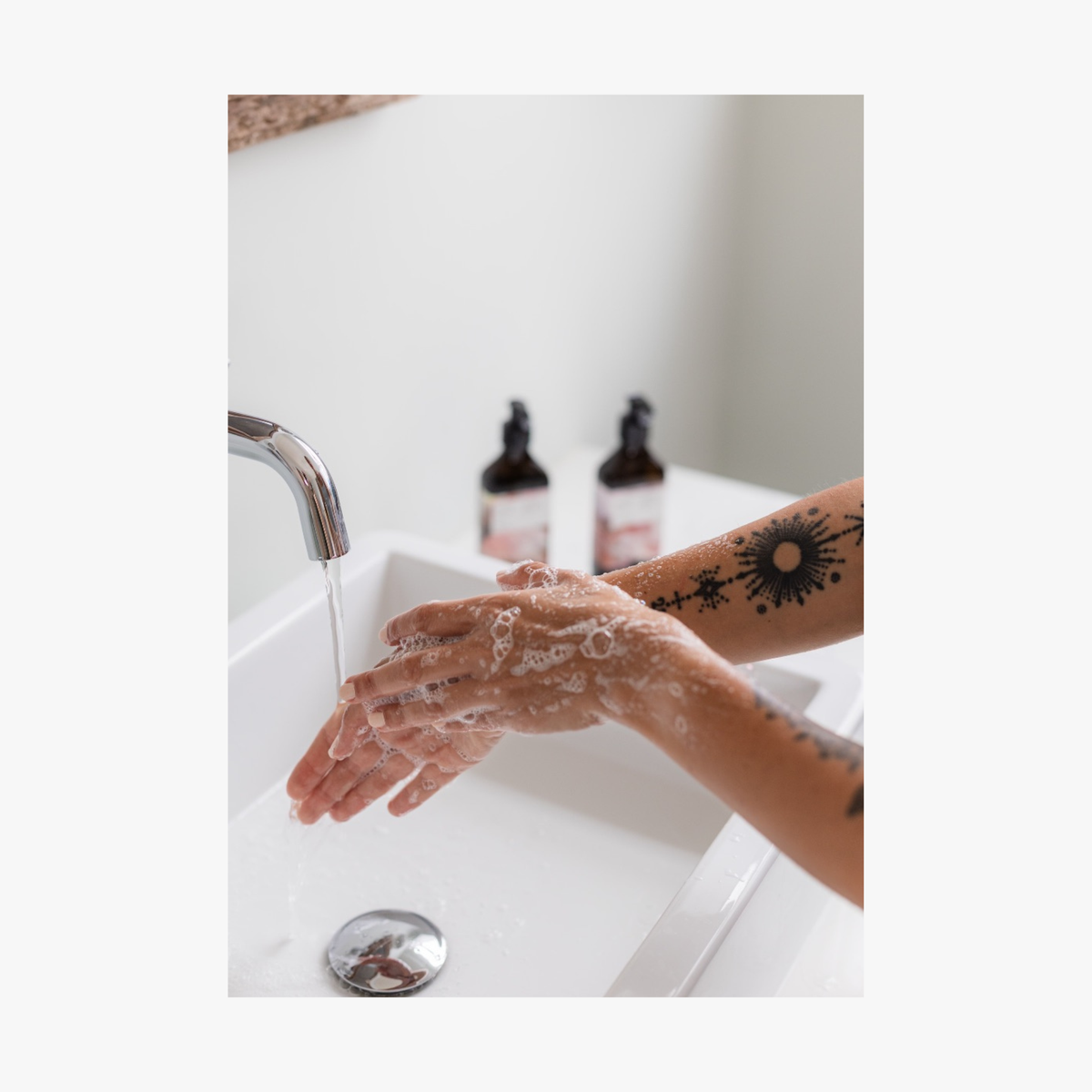 Person washing hands with luxury La-Eva hand and body wash under running water in a bathroom.