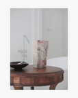 Lifestyle: A standing pouch of La-Eva spice salts with Valeska Hykel artwork label sits on a round wooden table beside a small black dish in a softly lit interior setting