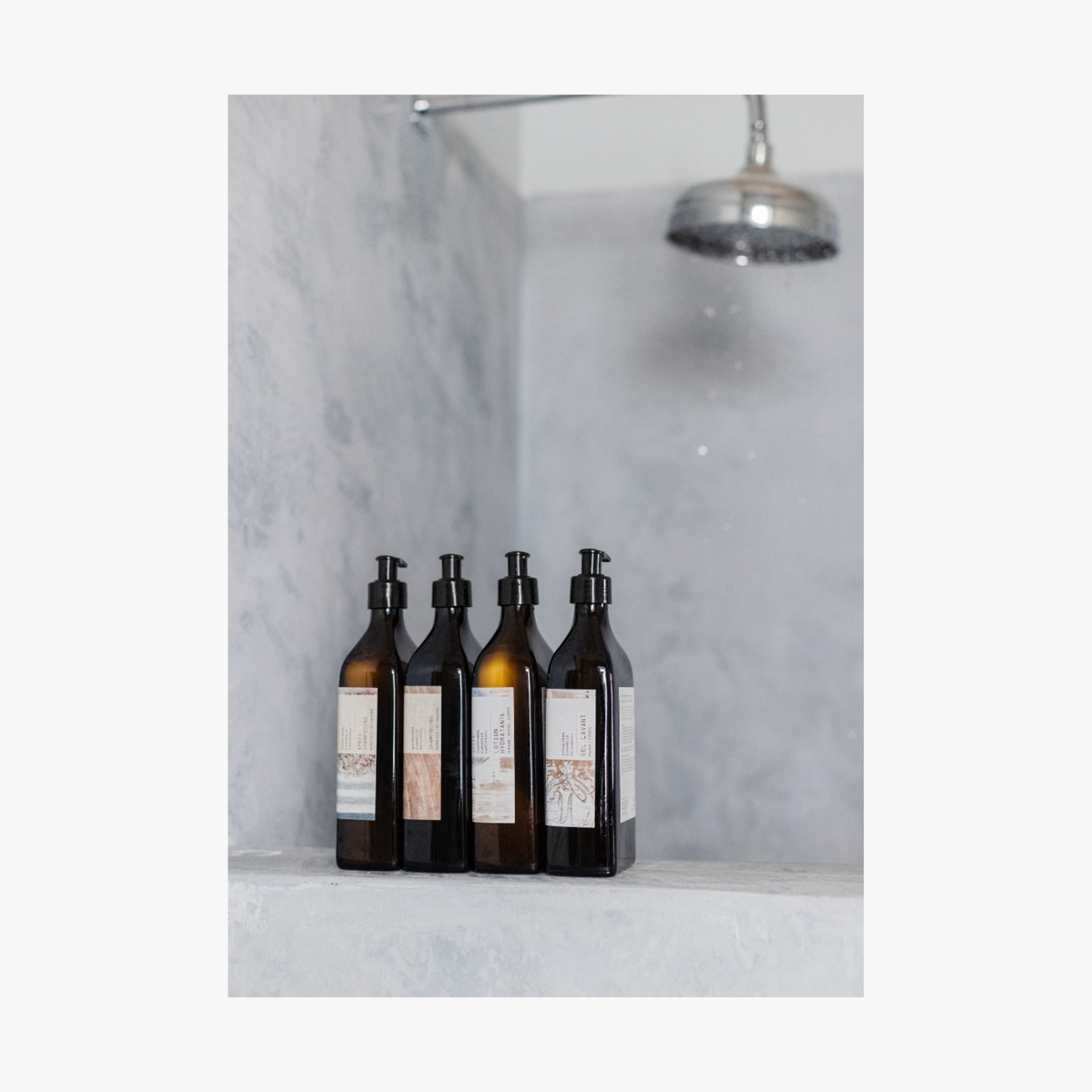 Set of five bottles of La-Eva spice collection with labels by Emma Cassi on a marble shelf against a marble wall.