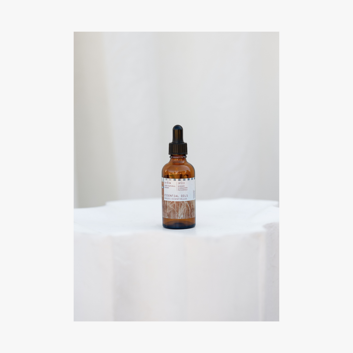 Lifestyle: La-Eva spice essential oil in amber glass bottle with pippette. Label features artwork by Emma Cassi