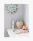 Casa Cubita ceramic plates and vases on a white surface against a light grey wall with spicy la-eva wash 
