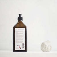 Back label showing ingredients of La-Eva Blu face and body lotion, 200ml glass bottle, next to white ceramic pomegranate